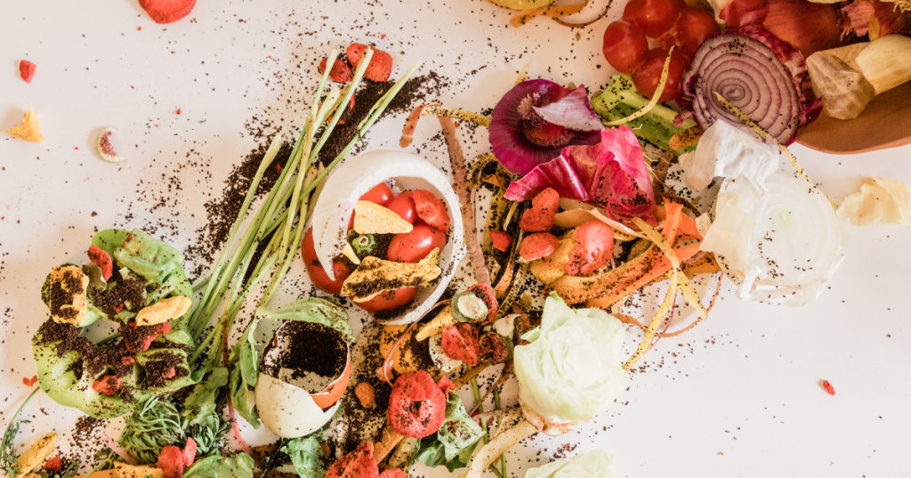 A messy assortment of food scraps, vegetable peels, coffee grounds, and discarded produce—potential renewable energy—scattered on a white surface.